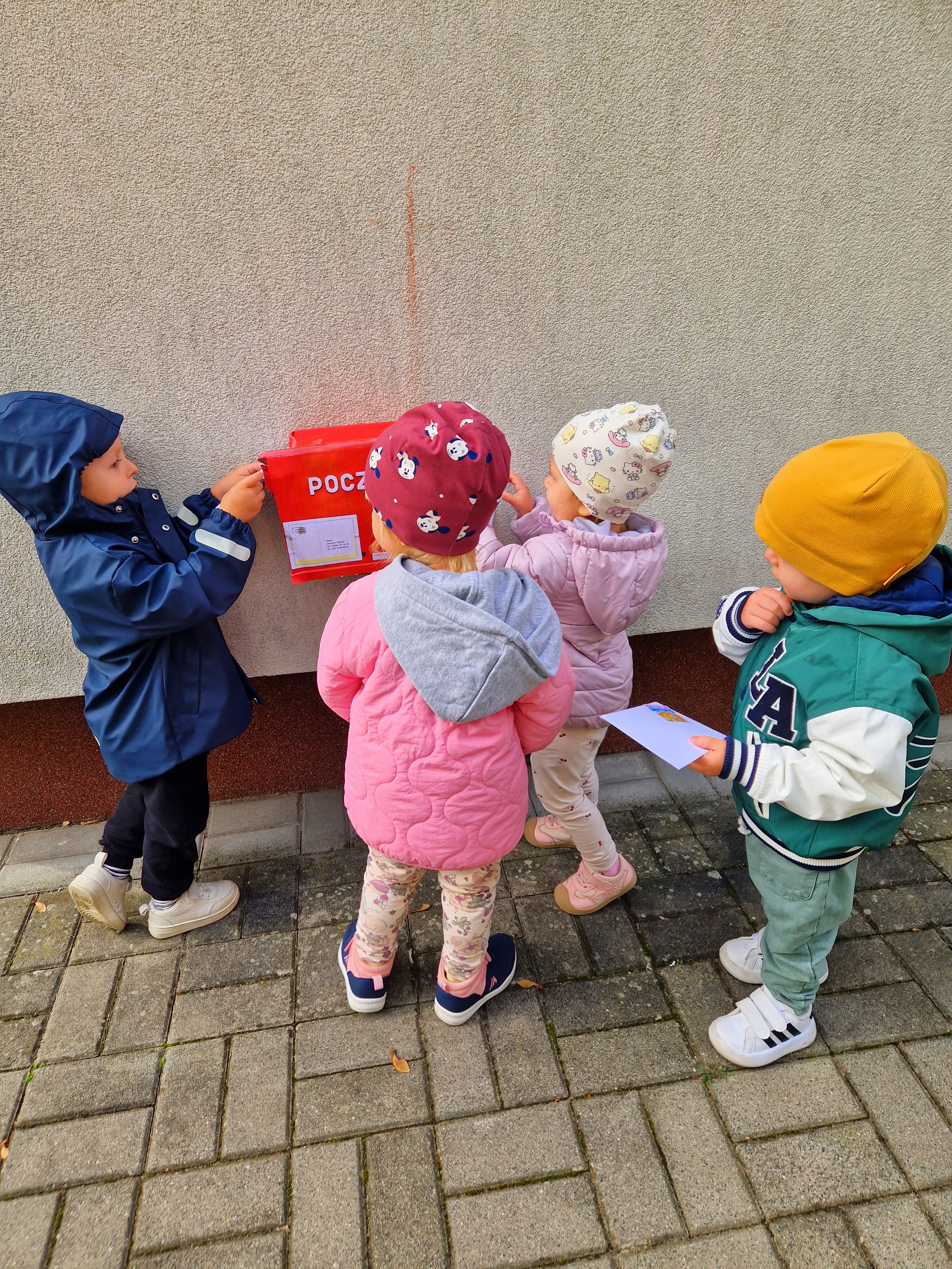 Zdjęcie przedstawia dzieci biorące udział w zabawach z okazji Międzynarodowego Dnia Poczty.