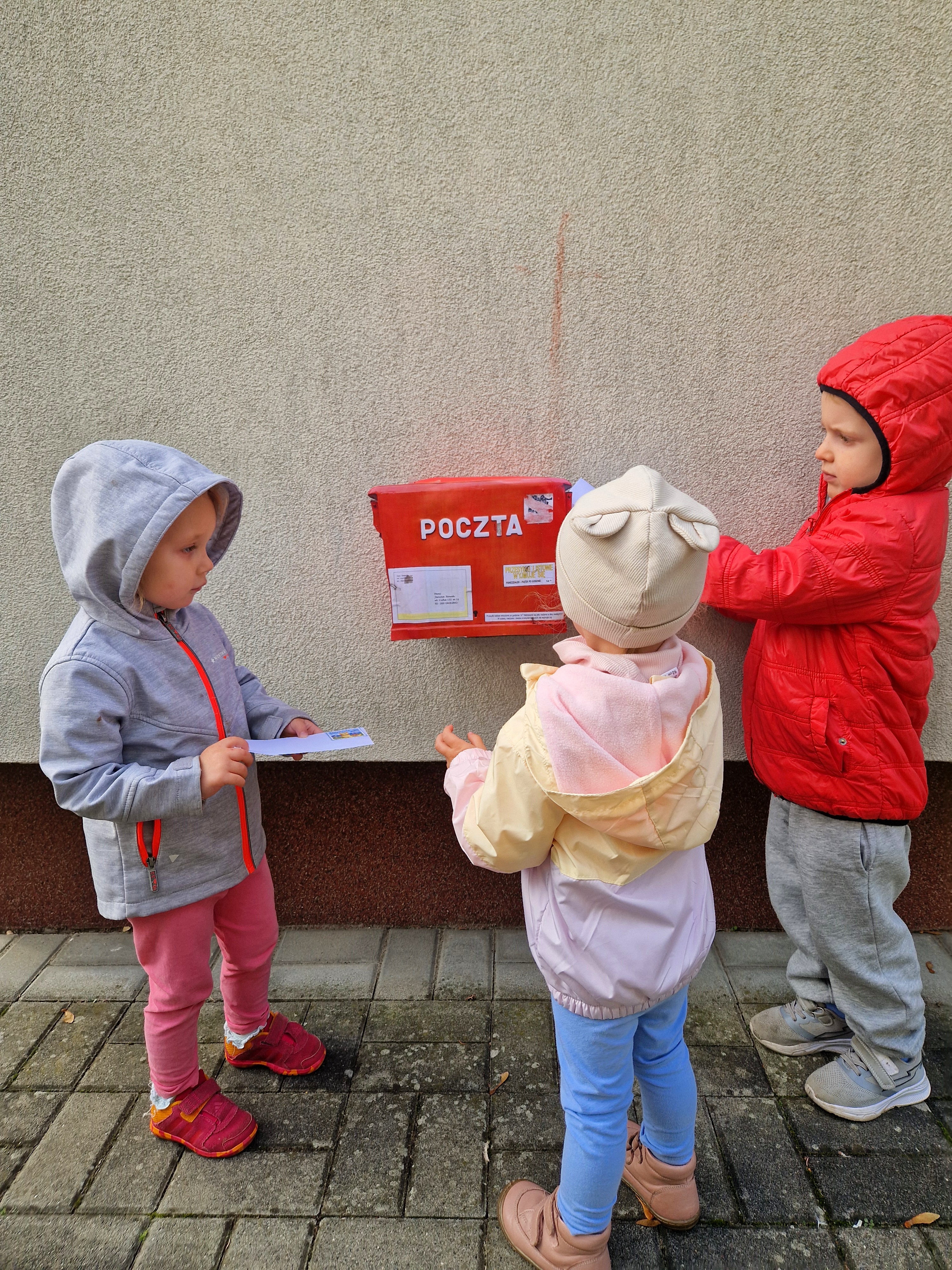 Zdjęcie przedstawia dzieci biorące udział w zabawach z okazji Międzynarodowego Dnia Poczty.